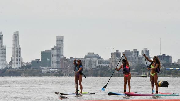 Tres mujeres disfrutan de un día realizando paddle surf en Rosario, uno de los destinos a los que se puede llegar en tren. (ENTE del turismo de rosario)